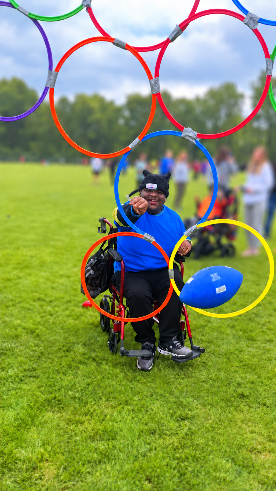 A joyful wheelchair user participating in an inclusive outdoor community activity with colorful hoops